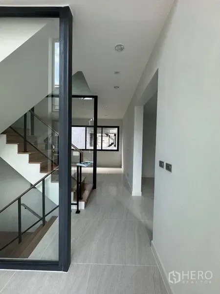 Townhouse for rent - Bright hallway with glass-framed staircase and large window in a modern Sukhumvit 77 townhouse.