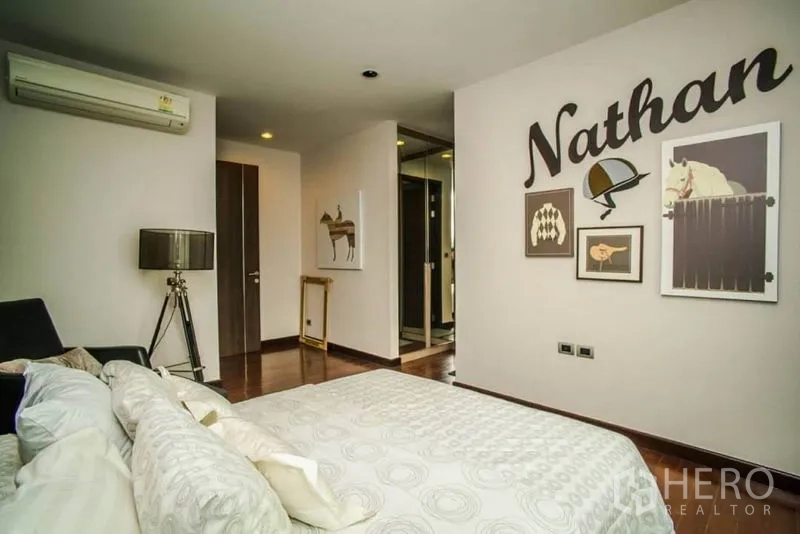 Townhouse for rent or sale in Watthana, Bangkok - Second bedroom view toward entrance and wardrobe with wall art