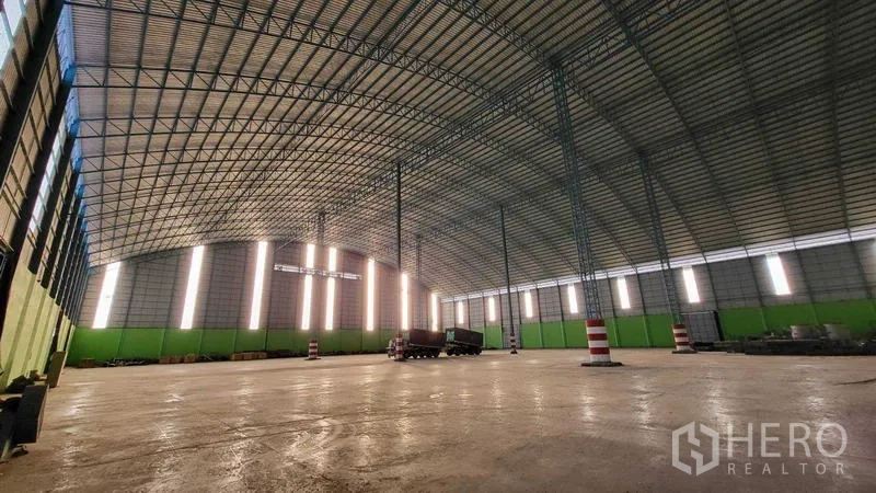 Factory for rent in Sai Noi, Nonthaburi - Panoramic view of spacious production hall with steel truss roof and striped columns.