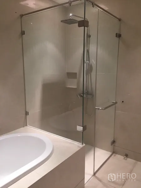 Condominium for rent in Khlong Toei, Bangkok - Bathroom with separate glass-enclosed rain shower and built-in bathtub.