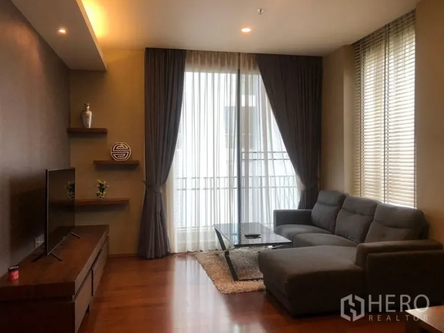 Condominium for rent or sale in Watthana, Bangkok - Bright living room with sliding door to balcony, sectional sofa and media console.
