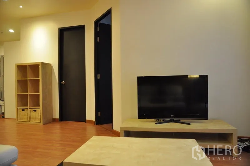Condominium for rent or sale in Khlong Toei, Bangkok - TV corner with open shelving, black doors and warm-toned wooden floor.