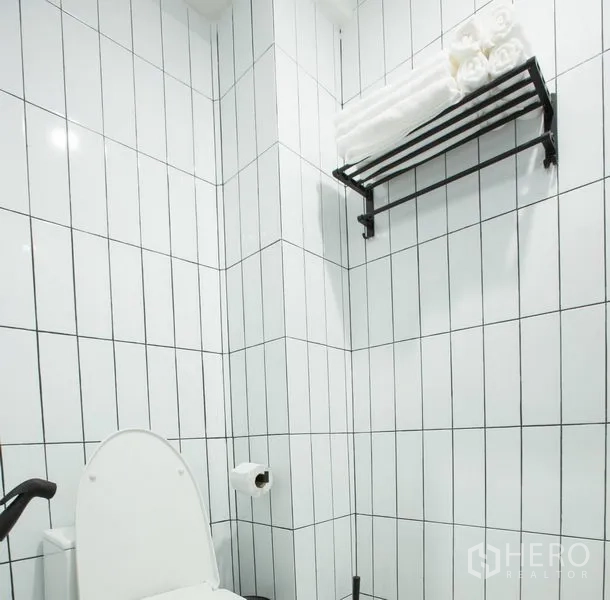 Townhouse for rent in Sathon, Bangkok - Clean bathroom finished with white vertical subway tiles and a wall-mounted towel rack.