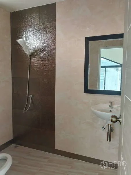 Factory for rent or sale in Sai Noi, Nonthaburi - Factory restroom with shower zone, brown feature tiles and wall-mounted sink.