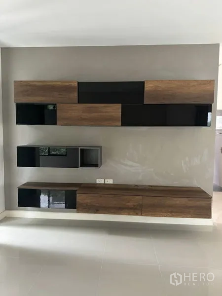 Detached House for rent in Samut Prakan - Close-up of modern wall-mounted media cabinet with wood and black panels.