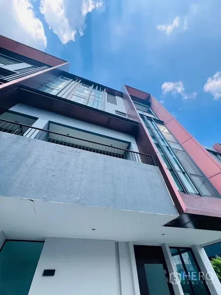 Home Office for sale in Bang Khen, Bangkok - Contemporary home office facade featuring red cladding, balconies and full-height glass under a blue sky.
