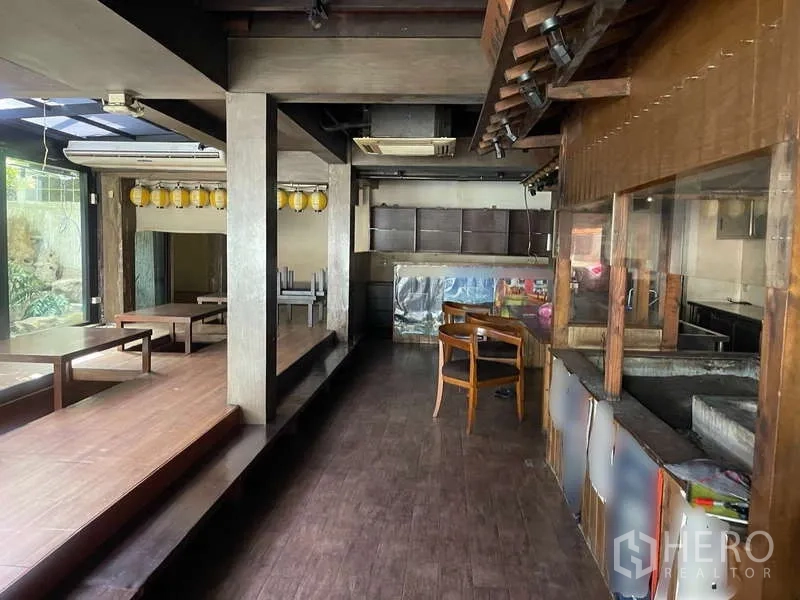 Detached House for rent in Watthana, Bangkok - Dining area with raised seating, lanterns and glass walls facing the garden.