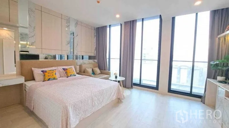 Condominium for rent or sale in Pathum Wan, Bangkok - Spacious bedroom with floor-to-ceiling windows and a city outlook.