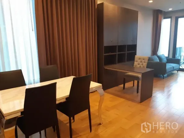 Condominium for rent in Khlong Toei, Bangkok - Open-plan living and dining area with marble-top table and built-in shelving.
