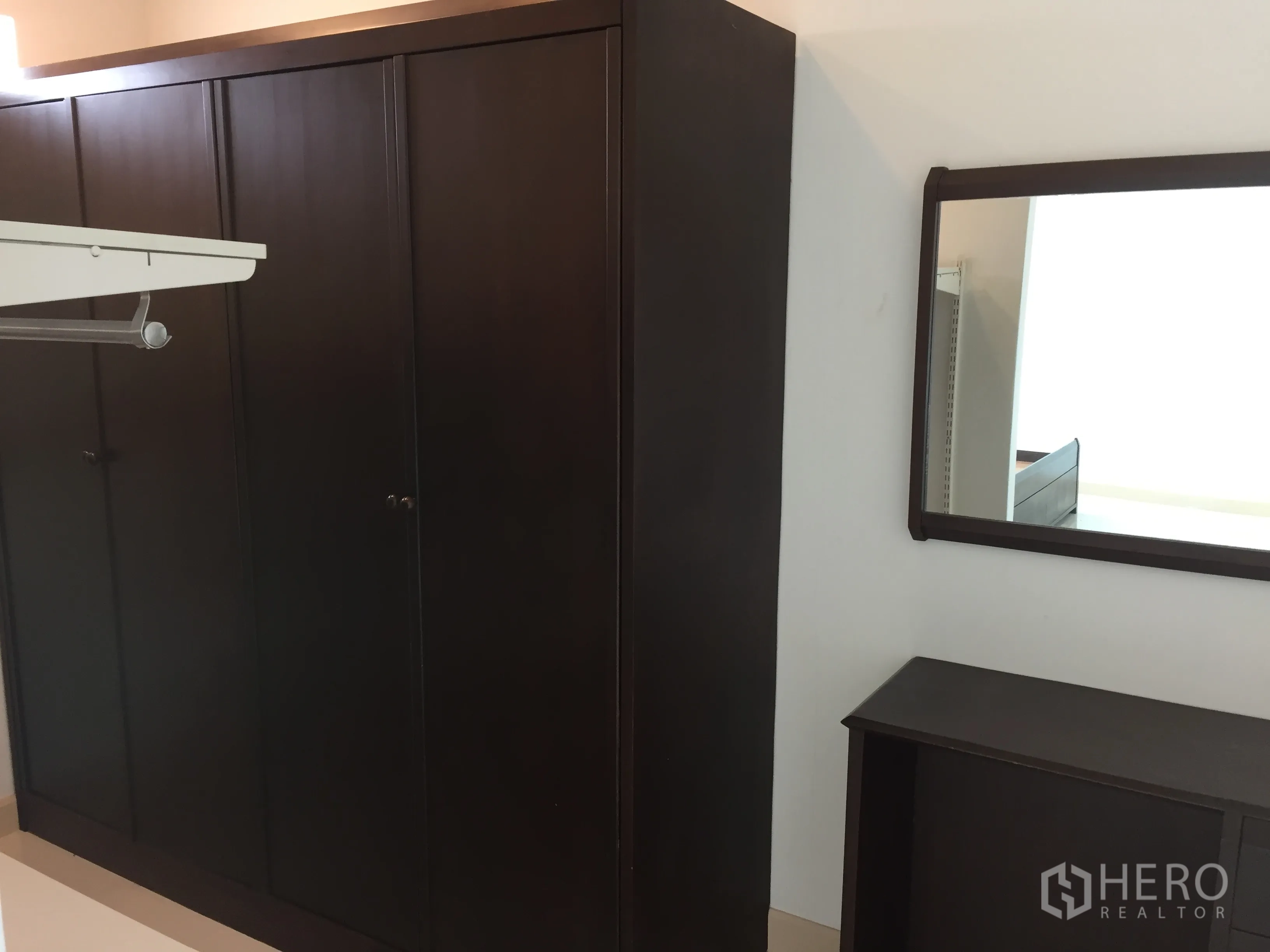 Townhouse for rent in Din Daeng, Bangkok - Large dark wood wardrobe with matching wall mirror and compact dresser in a simple dressing area.