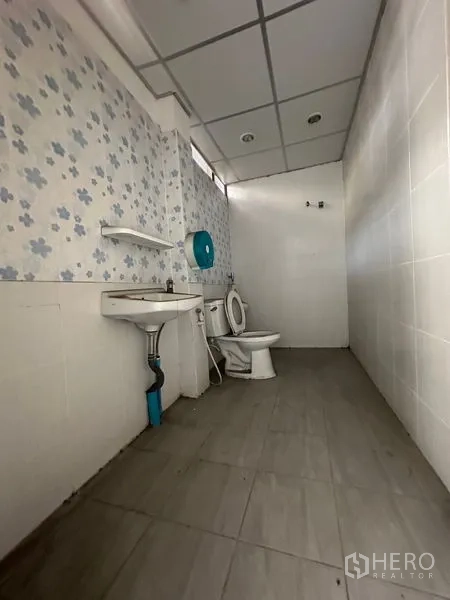 Shophouse for rent in Bang Na, Bangkok - Bathroom with toilet, sink and tiled walls inside the property.