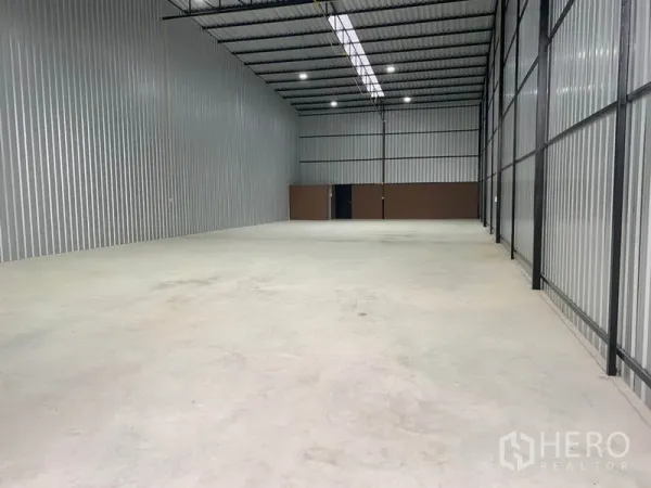 Warehouse for rent in Khlong Luang, Pathum Thani - Spacious warehouse interior with high steel roof, skylight strip, LED lighting, and smooth concrete floor.