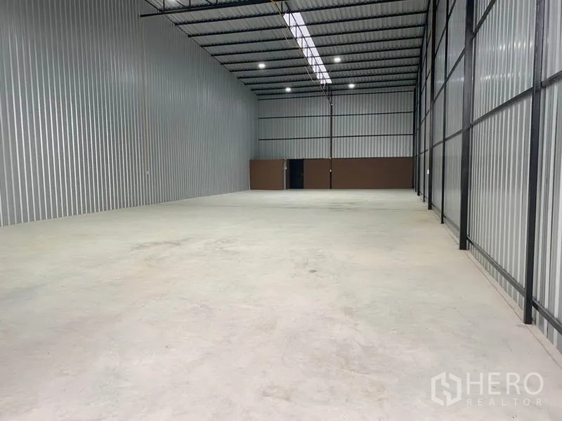 Warehouse for rent in Khlong Luang, Pathum Thani - Spacious warehouse interior with high steel roof, skylight strip, LED lighting, and smooth concrete floor.