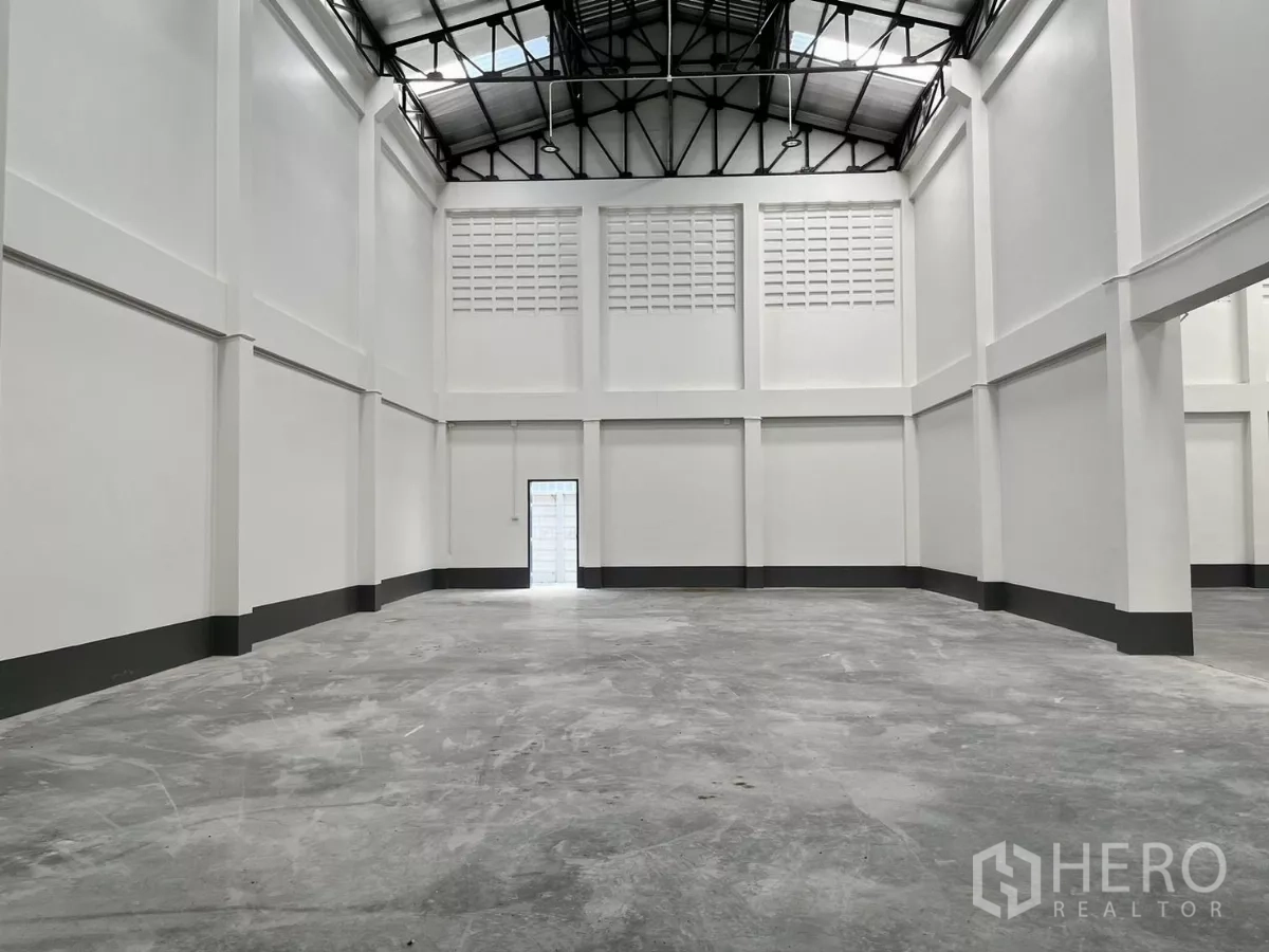 Warehouse for rent in Mueang Samut Sakhon, Samut Sakhon - Empty warehouse space with tall white walls, durable concrete floor, side door and insulated steel roof.