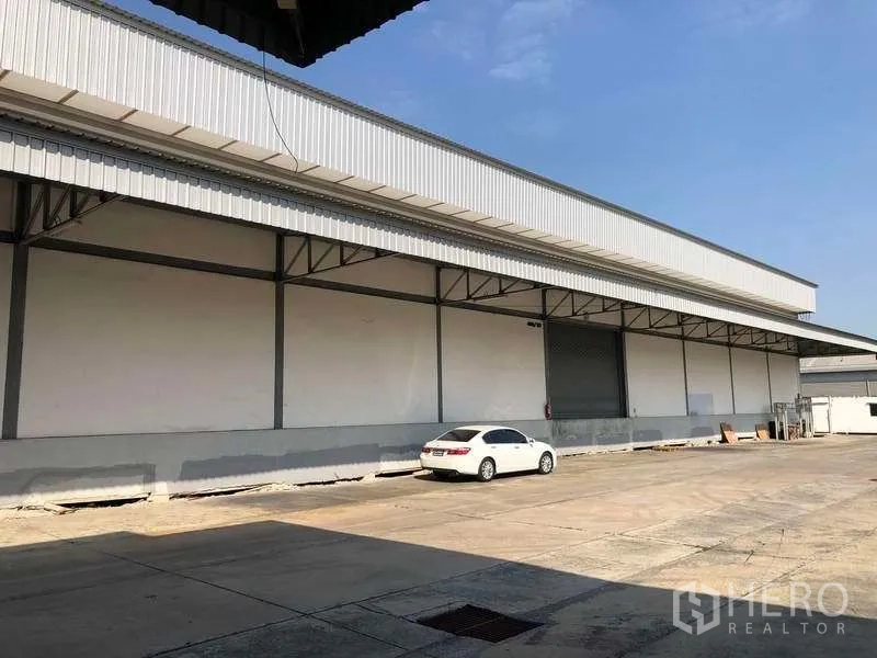 Warehouse for rent in Bang Phli, Samut Prakan - Long warehouse facade with roller shutter doors and wide driveway for circulation.
