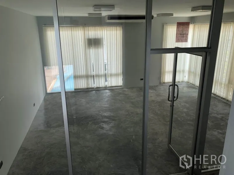 Home Office for rent in Wang Thonglang, Bangkok - Bright room viewed through a glass door with windows and vertical blinds.