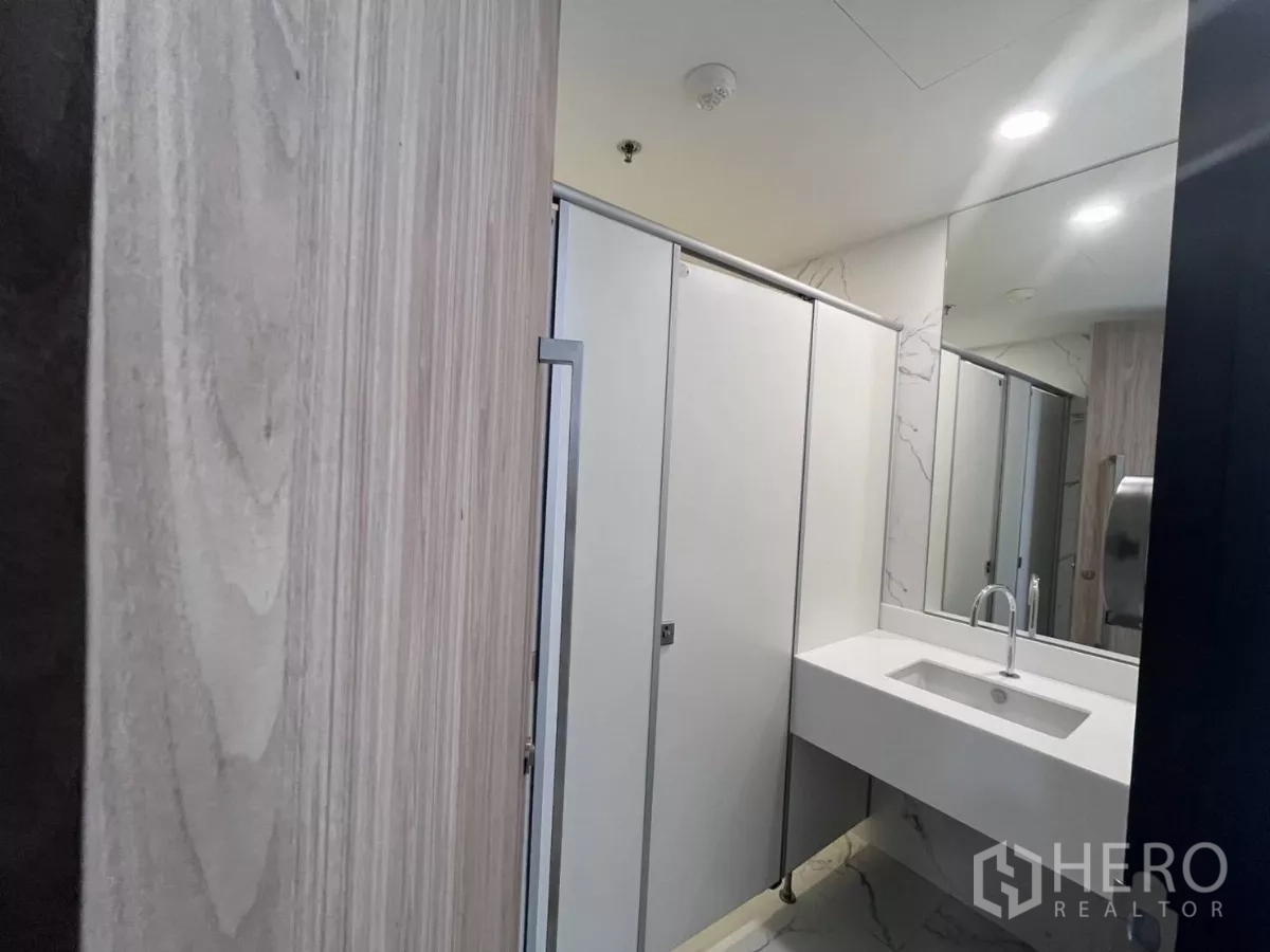 Office Space for rent in Din Daeng, Bangkok - Renovated restroom with white vanity, large mirror and partitioned stalls in a marble-accent finish.