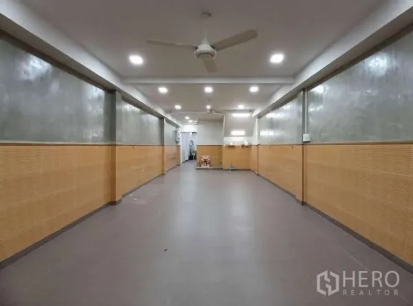 Shophouse for rent in Phra Khanong, Bangkok - Long ground-floor commercial hall with tiled floor, ceiling fans and downlights, ready for retail or office use.
