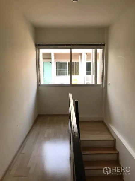 Townhouse for rent in Suan Luang, Bangkok - Stair landing with window providing natural light to the upper floor.