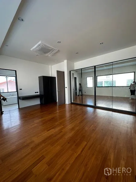 Detached House for rent in Watthana, Bangkok - Large master bedroom with wood floors, mirrored wardrobes, and ample natural light.