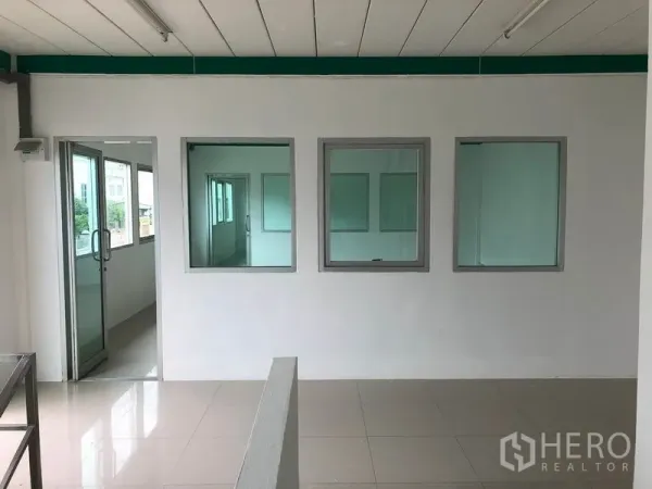 Factory for rent in Lam Luk Ka, Pathum Thani - Bright internal office space with glass windows and tiled floors overlooking the production area.