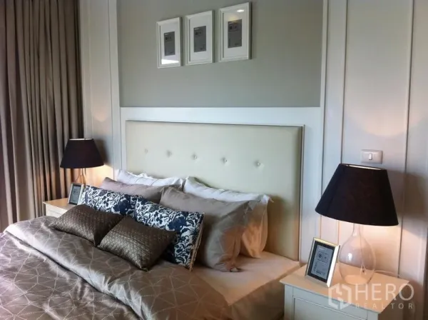 Condominium for rent in Bangkok - Close-up of stylish bed with padded headboard, decorative pillows and twin lamps.