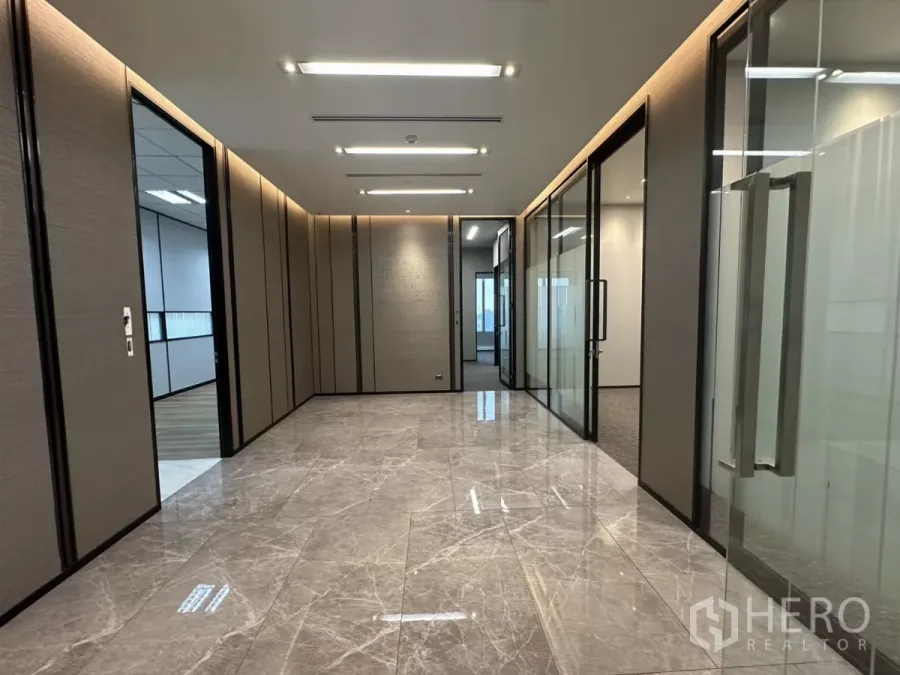 Office Space for rent in Watthana, Bangkok - Marble-floored corridor with glass-partitioned offices and recessed lighting in a premium workspace.