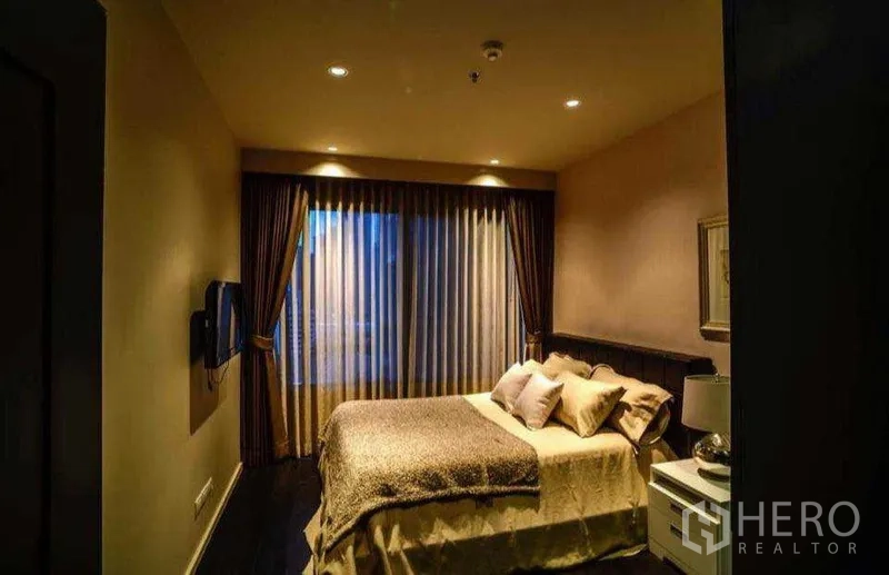 Condominium for rent or sale in Khlong Toei, Bangkok - Guest bedroom alternate view with wall-mounted TV and ambient lighting.