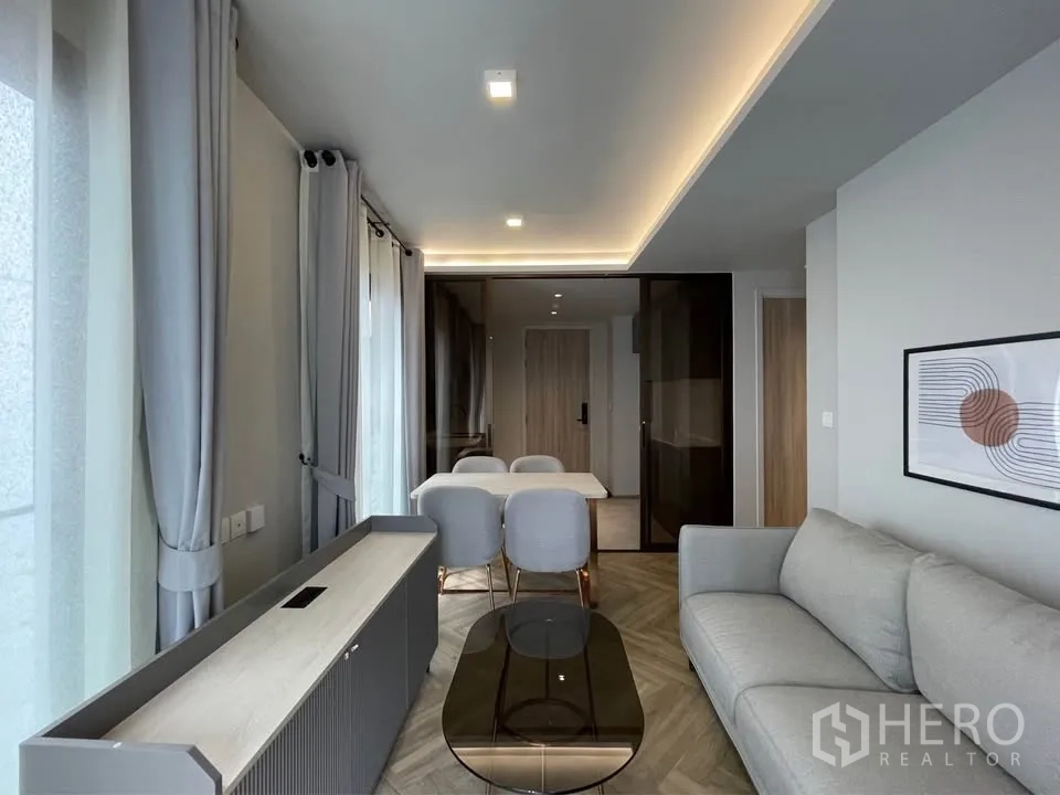 公寓 for rent in Watthana, Bangkok - 起居区配灰色沙发、电视柜、餐桌椅与大窗帘。