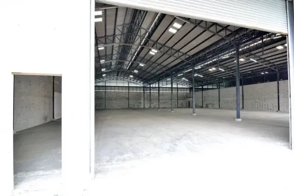 Warehouse for rent in Phra Pradaeng, Samut Prakan - Open-plan warehouse viewed from the large rolling door with clear-span layout and lighting.