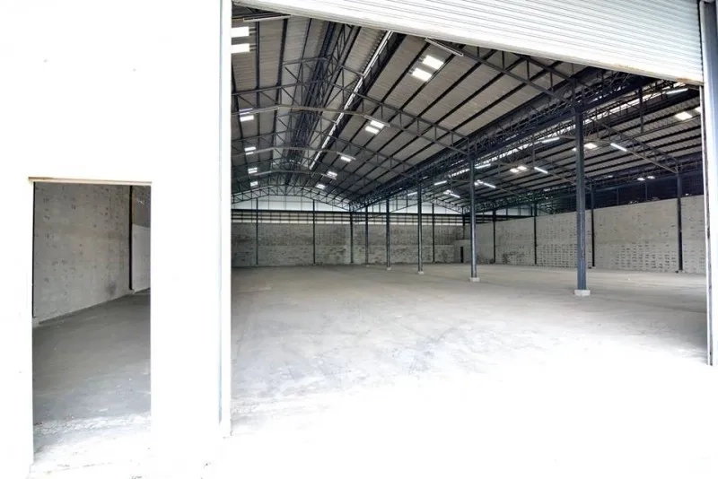 Warehouse for rent in Phra Pradaeng, Samut Prakan - Open-plan warehouse viewed from the large rolling door with clear-span layout and lighting.