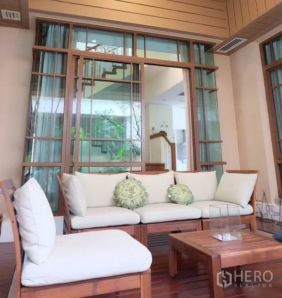 Detached House for rent in Watthana, Bangkok - Covered terrace with cushioned wooden seating and glass doors opening to the home.