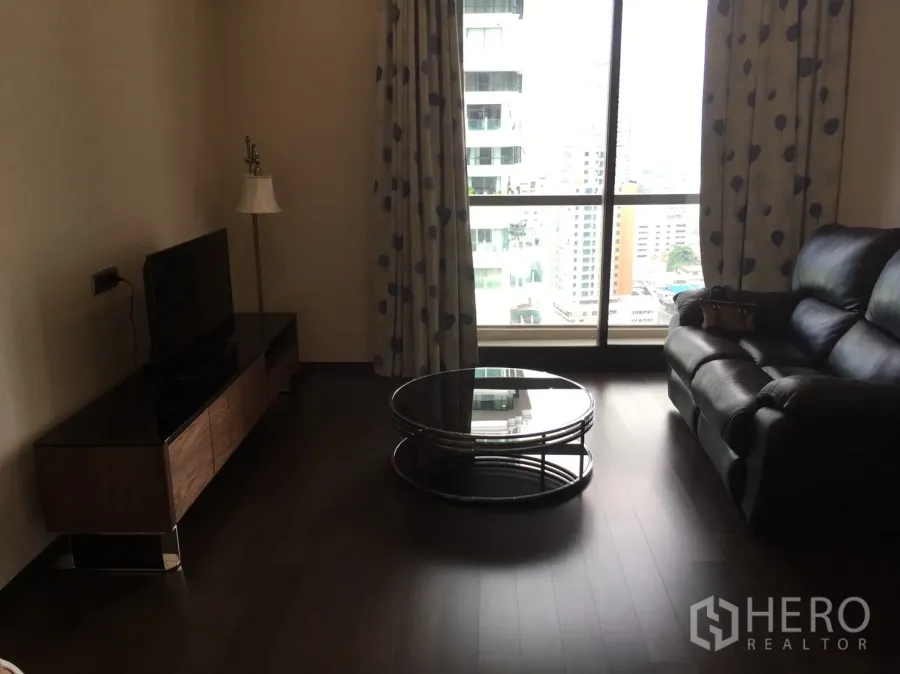 公寓 出租在Watthana, Bangkok - 客厅配黑色皮沙发、圆形玻璃茶几、电视柜与落地窗城市景观