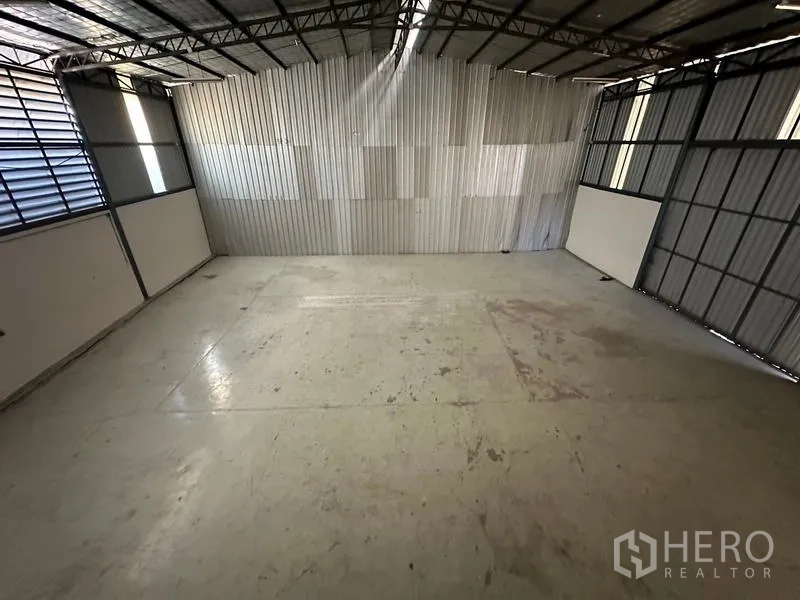 Office Space for rent - Empty warehouse bay with steel roof trusses and sealed concrete floor.