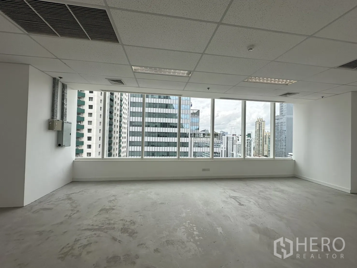 Office Space for rent in Watthana, Bangkok - Unfurnished office with acoustic tile ceiling, strip lighting, and skyline views through wide windows.