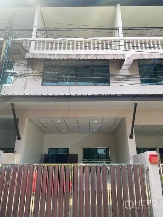 Townhouse for rent in Suan Luang, Bangkok - Three-storey townhouse facade with gated carport, balconies and large windows in On Nut, Bangkok.