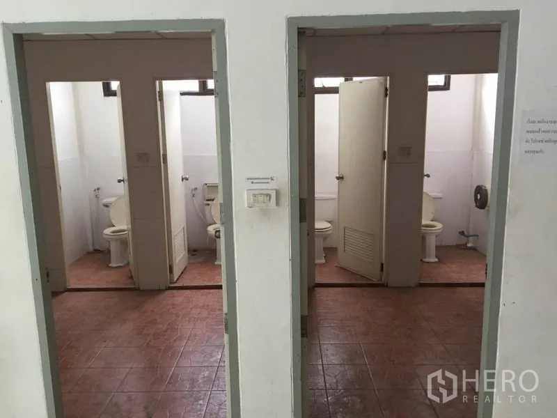 Warehouse for rent in Saphan Sung, Bangkok - Clean staff restrooms with tiled floors and separate toilet stalls within the facility.