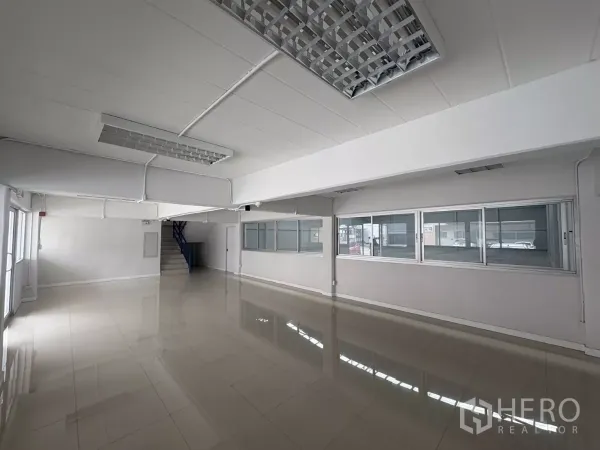 Factory for rent in Bang Phli, Samut Prakan - Spacious ground-floor office with glossy tiles, fluorescent lighting and an internal staircase.