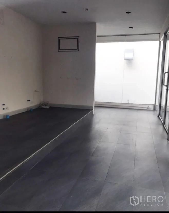 Retail Space for rent in Watthana, Bangkok - Empty shop interior with gray floor tiles, white ceiling with downlights, and sliding glass entry.