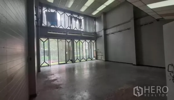 Shophouse for rent in Watthana, Bangkok - Double-height ground floor with glass folding doors and loft-style mezzanine.