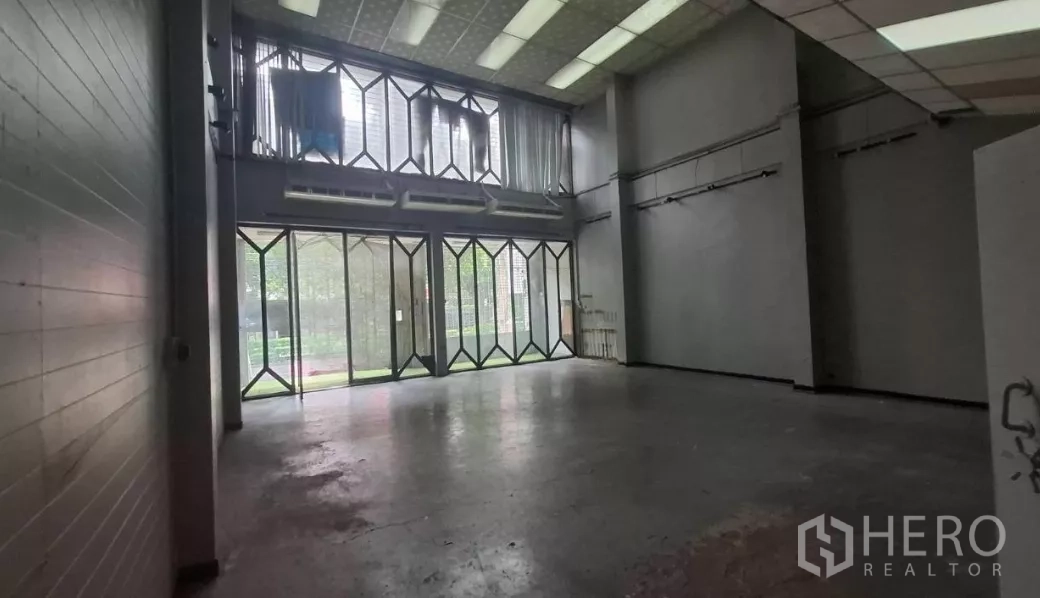 Shophouse for rent in Watthana, Bangkok - Double-height ground floor with glass folding doors and loft-style mezzanine.