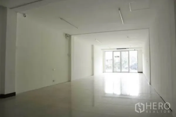 Retail Space for rent in Watthana, Bangkok - Bright open-plan retail interior with white walls, tiled floors, ceiling strip lights, and a full-width glass storefront.