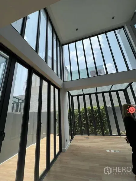 สำนักงานที่บ้าน ขายในWang Thonglang, Bangkok - ห้องนั่งเล่นเพดานสูงสองชั้น ผนังกระจกเต็มบาน พื้นไม้ และพื้นที่สวนภายใน โฮมออฟฟิศสมัยใหม่