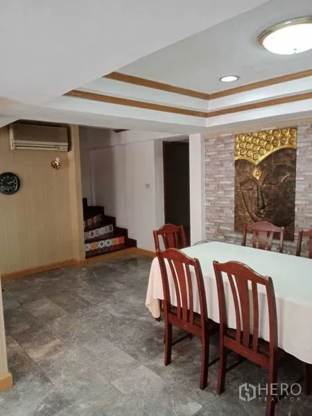 Townhouse for rent in Khlong Toei, Bangkok - Dining area with a six-seat table, decorative ceiling, and staircase in the Bangkok townhouse.