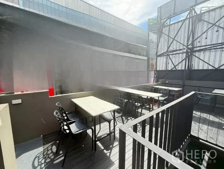 Retail Space for rent in Watthana, Bangkok - Sunlit rooftop dining area with multiple tables and black chairs beside the railing.