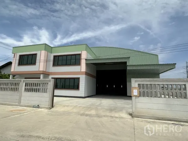 Factory for rent or sale in Sai Noi, Nonthaburi - Modern factory for sale in Sai Noi, Nonthaburi with two‑storey office wing, green metal roof, wide driveway and concrete perimeter wall.