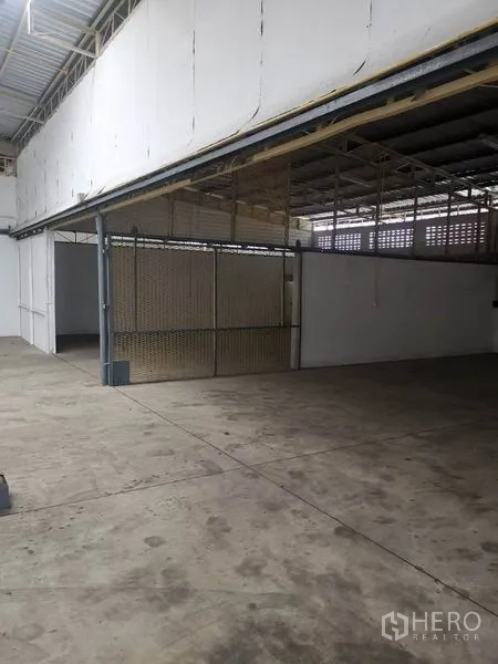 Warehouse for rent in Suan Luang, Bangkok - Partitioned storage bay with metal mesh sliding gate under the covered roof.