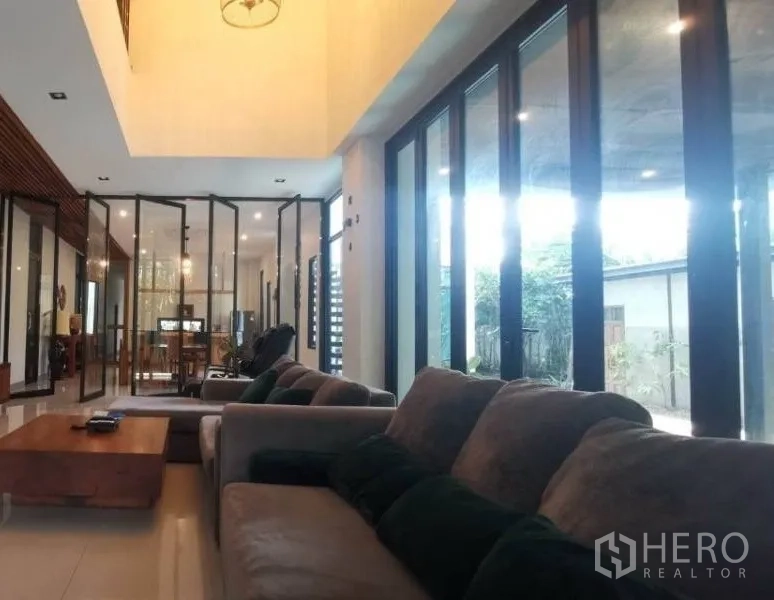 Detached House for sale in Pak Kret, Nonthaburi - Sofa lounge facing floor-to-ceiling sliding doors and a double-height ceiling filled with light.