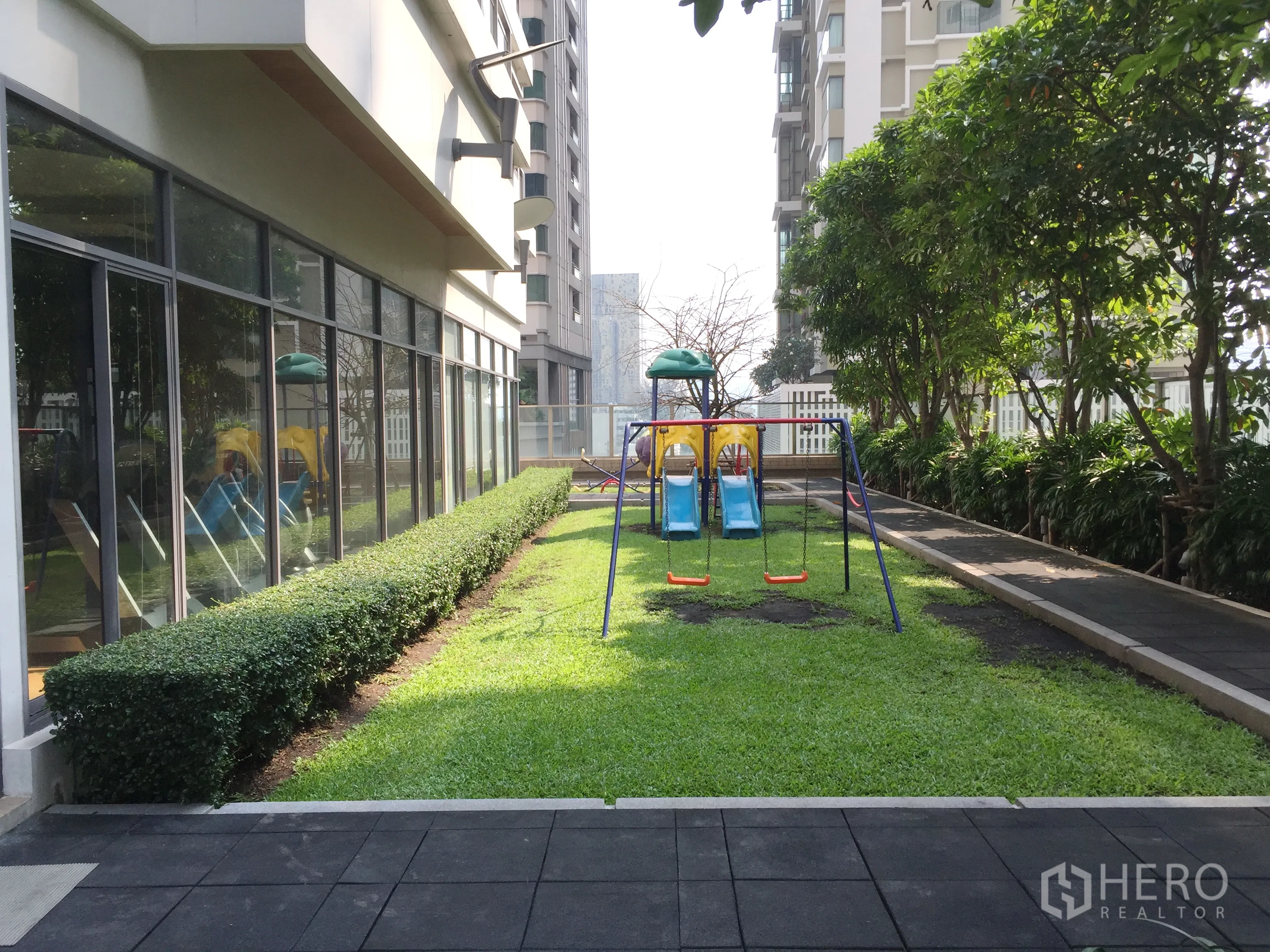 Condominium for rent in Khlong Toei, Bangkok - Children’s playground with swings and slides in landscaped garden.