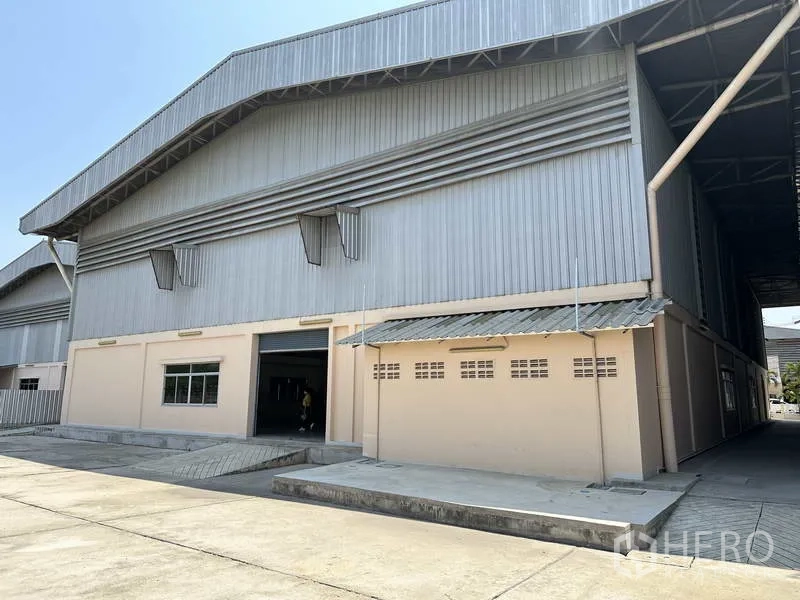 工厂 出租 - 工厂后侧外观，设装卸坡道、卷闸门与宽阔混凝土作业区。